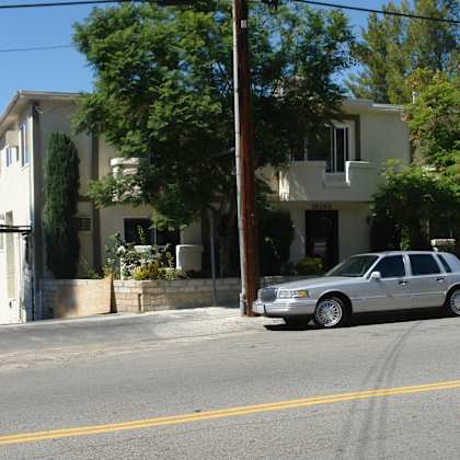 a silver car is parked on the side of a street in front of a house.