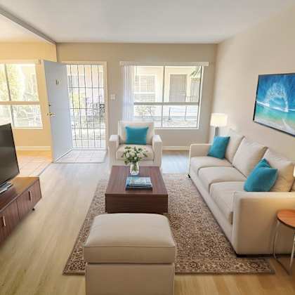 a living room with a white couch, a coffee table, and a television.