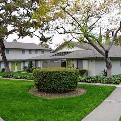a white house with a lawn and trees in front of it at terramonte apartment homes, pomona, 91767