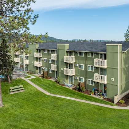 apartment complex with a green lawn and a tree.