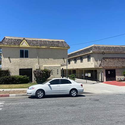a silver car is parked in front of a building with a red awning.