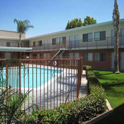 a pool surrounded by a fence and trees.