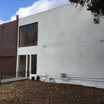 a white building with a brown door and windows.