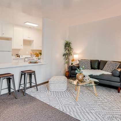 a living room with a couch and a kitchen with a bar and stools at university park, azusa, 91702