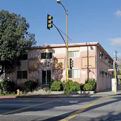 a pink building with a tree out front