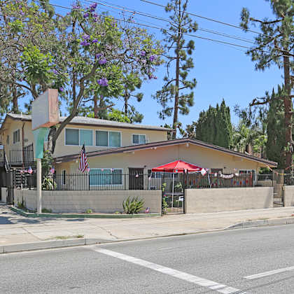 a building with a red umbrella is situated on the corner of a street.