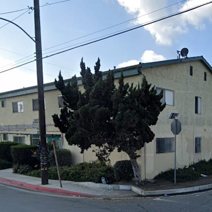 a street view of a residential area with a house, cars, and trees.