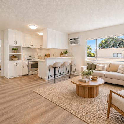a well-lit, spacious kitchen and living room with wooden flooring and furniture.