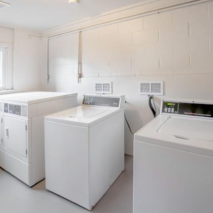 a laundry room with a washer, dryer, and ironing board.