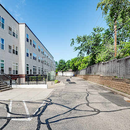 a parking lot in front of a building with a wooden fence on the right side.