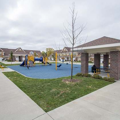 a playground with a blue slide and a brown pavement.