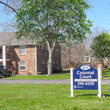 a sign for colonial court apartments is in front of a house.