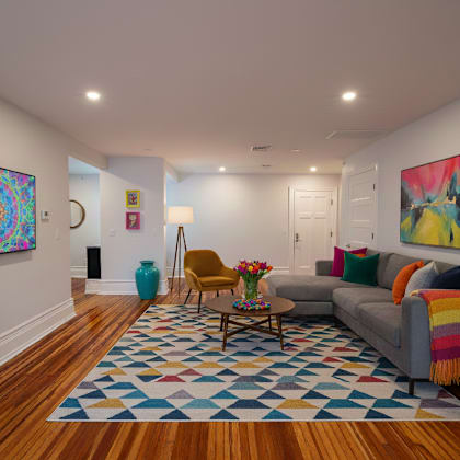 a living room with a grey couch and a blue vase.