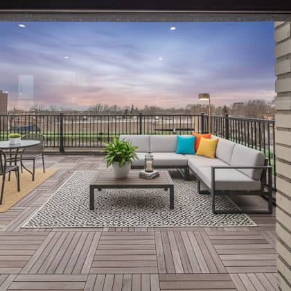 a balcony with a table, chairs, and a potted plant.