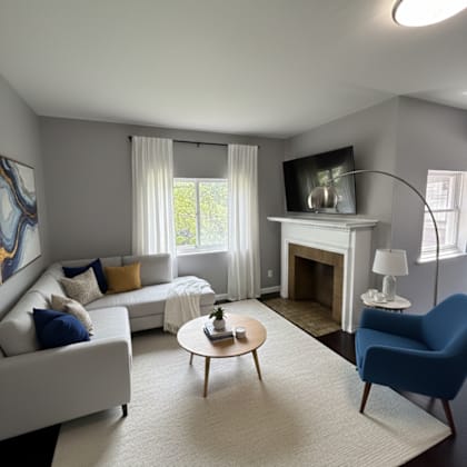 a living room with a white couch, a blue chair, a coffee table, and a fireplace.