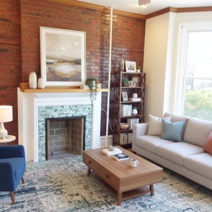 a living room with a blue chair, a white couch, and a fireplace.
