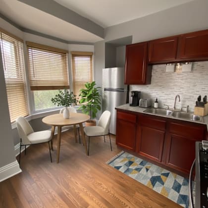 a kitchen with wooden floors and a white brick backsplash.