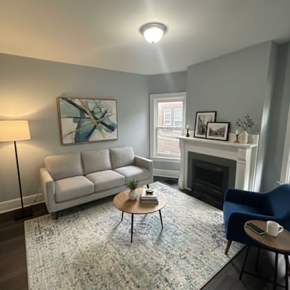 a living room with a white couch, a blue chair, a coffee table, and a fireplace.