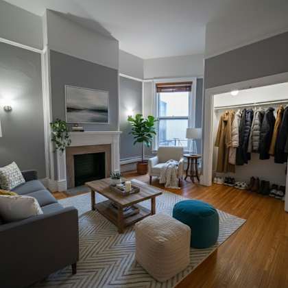 a living room with a grey couch, a coffee table, a fireplace, and a wardrobe.