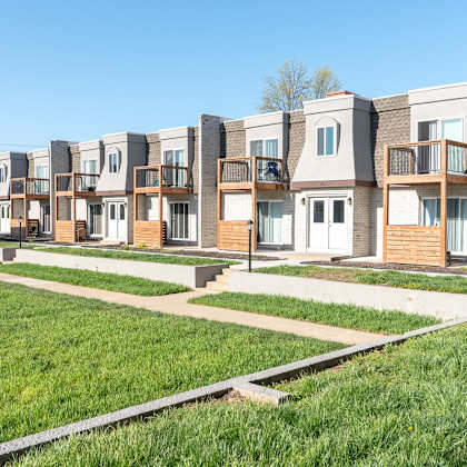 a row of modern townhouses with green lawns in front.