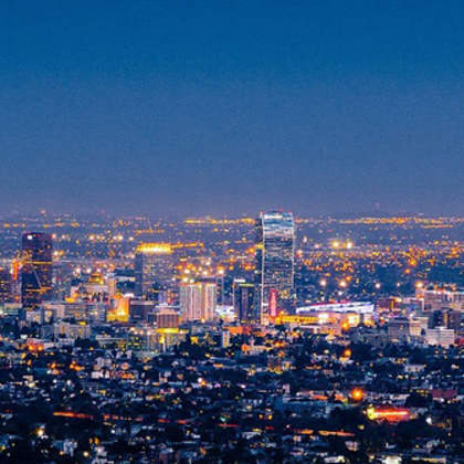 A cityscape at night with buildings illuminated against a dark sky.
