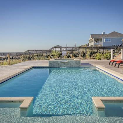 a swimming pool with a wooden deck and a red bench.