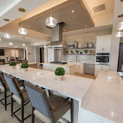 a large kitchen with a long counter and chairs in front of a table