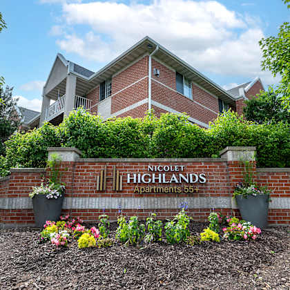 the image shows a brick building with a sign that reads "nicolet highlands apartments 55+".