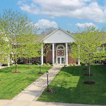 a building with a white roof and a red door is surrounded by green trees.