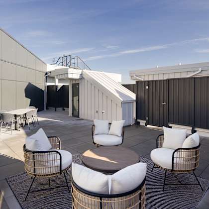 a patio with white chairs and a table.
