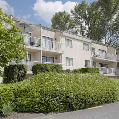 apartment building with green bushes in front.