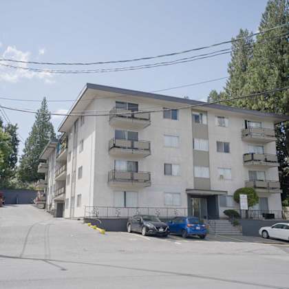 a white apartment building with cars parked in front.