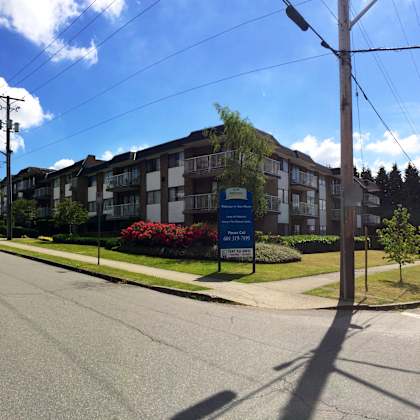 a street view of a residential area with apartment buildings and a sign for a real estate agency.