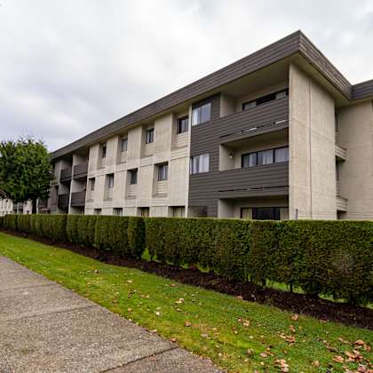 a modern building with a grey facade and a concrete walkway in front.