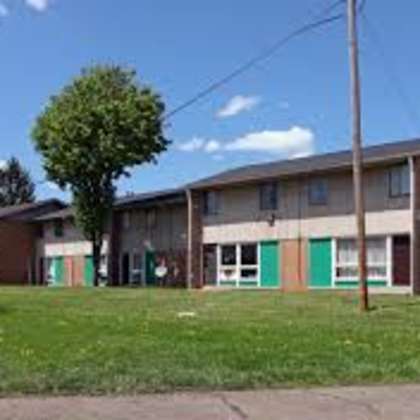 an old building with green doors and a grass field