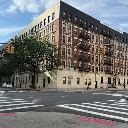 a street view of a city intersection with cars and a large building.