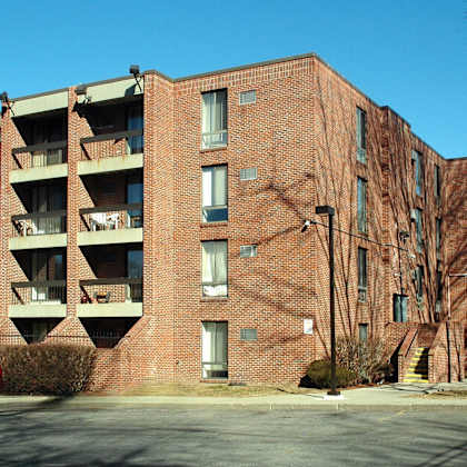 a red car is parked in front of a large brick building.