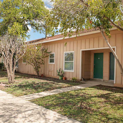 the front of a house with a sidewalk and trees