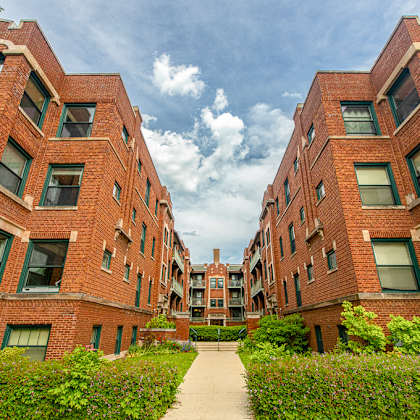 a red brick building with green shutters and a walkway in the middle.