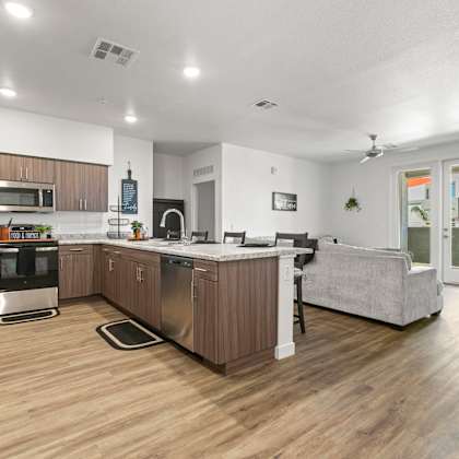 a modern kitchen with stainless steel appliances and wooden flooring.