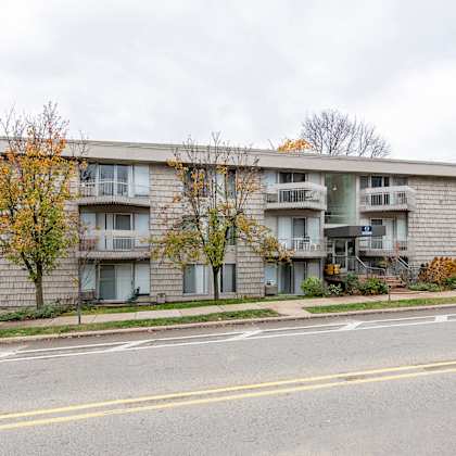 a grey apartment building with a car parked in front.