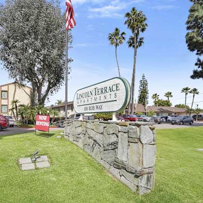 a sign for lincoln terrace apartments stands in front of a stone wall.