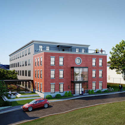 a red car is parked on the side of a road in front of a building.