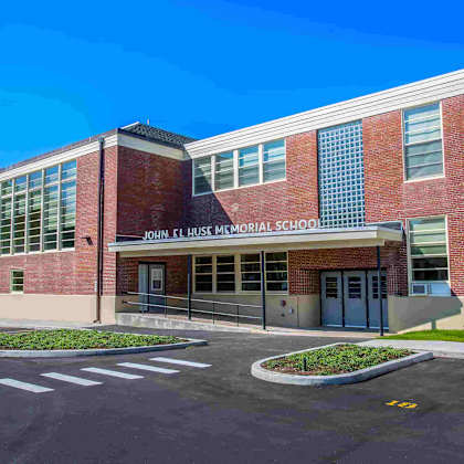 john f. kennedy memorial school is a red brick building with a parking lot in front.