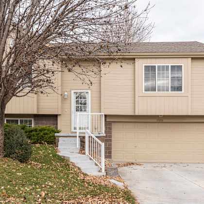 a beige house with a white door and a small porch.