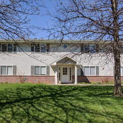 a house with a grey roof and a white door is surrounded by a green lawn.