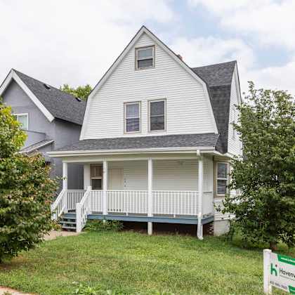 a two-story house with a front porch and a sign that says