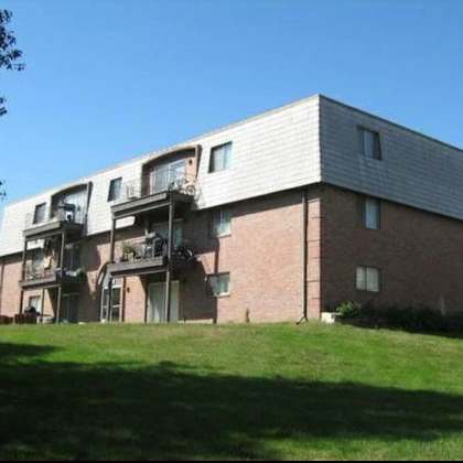 a red brick building with a white roof and a balcony on the second floor.