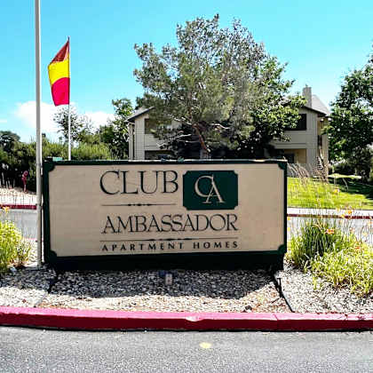 sign for club ambassador apartment homes is displayed in front of a building.