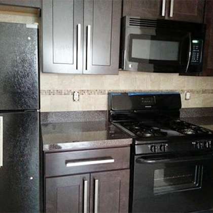 a black refrigerator with a magnet on it sits next to a black stove in a kitchen.